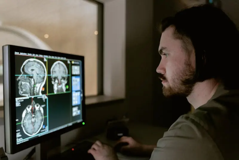A man examines MRI images displayed on a computer screen, focused on the details of the scans.