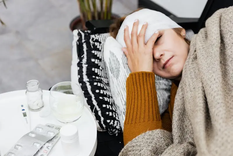 A woman with a visible head injury lies on a couch, looking uncomfortable and in pain.